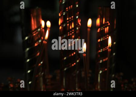Fire of memory. Turning to God. Silent prayer. A burning candles in the dark against the background of the iconostasis in the old church Stock Photo