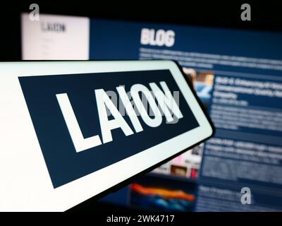 Smartphone with logo of Large-scale Artificial Intelligence Open Network (LAION) in front of website. Focus on center-left of phone display. Stock Photo