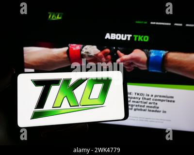 Person holding mobile phone with logo of American media company TKO Group Holdings Inc. in front of business web page. Focus on phone display. Stock Photo