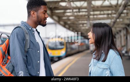 a young couple swearing and argueing with each othe at the train station on the platform The concept of disagreements in the family Stock Photo