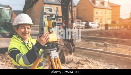 Construction site engineer woman in safety equipment working with surveying total station EDM instrument. Building, developing, construction and archi Stock Photo