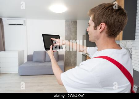 Worker with tablet computer checking alarm system indoors. Stock Photo