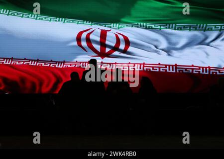 Tehran, Iran. 18th Feb, 2024. Iranian visitors stand next to a huge flag of Iran during the 24th Iran Media Expo in Tehran. During this event, journalists will exchange views on the latest developments in the field of media. Various news agencies, newspapers, news websites, and magazines have showcased their recent achievements in news gathering and information dissemination. (Credit Image: © Rouzbeh Fouladi/ZUMA Press Wire) EDITORIAL USAGE ONLY! Not for Commercial USAGE! Credit: ZUMA Press, Inc./Alamy Live News Stock Photo