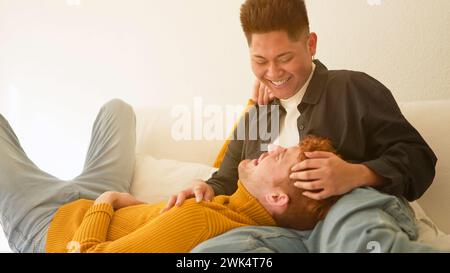 Gay couple in love smiling together lying on the sofa Stock Photo