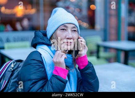 a beautiful happy asian woman in blue hat tourist travelling around the world and exploring new places, speaking by phone Stock Photo
