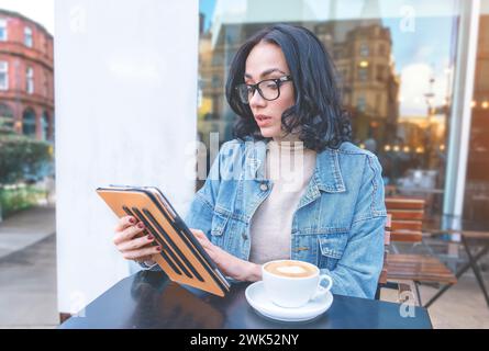 happy woman student e-learning distance training course study working in the cafe, drinking coffee, watching online education, webinar using a laptop Stock Photo