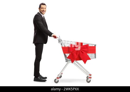 Full length profile shot of a businessman with an empty shopping cart tied with a red ribbon bow isolated on white bacakground Stock Photo