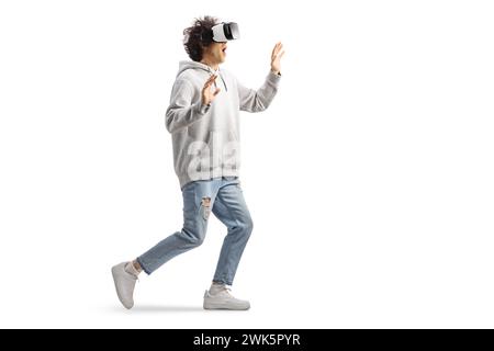 Young casual man with a VR headset walking and touching with hands isolated on white background Stock Photo