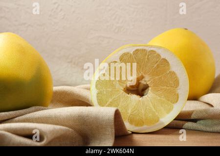 Tasty whole and cut pomelo fruits with napkin on wooden table Stock Photo