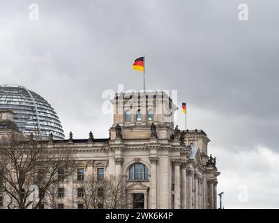 Reichstag building exterior with the German flag on the rooftop. The historical governmental house is a travel destination. The dark sky is dramatic. Stock Photo