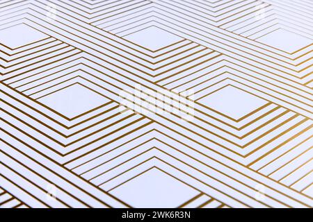 Shiny gold geometric lines on white paper from an angle Stock Photo