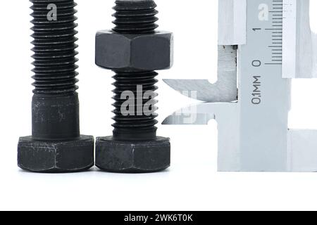 Caliper measure two adjacent black bolts with hexagonal heads, lying on a white background Stock Photo