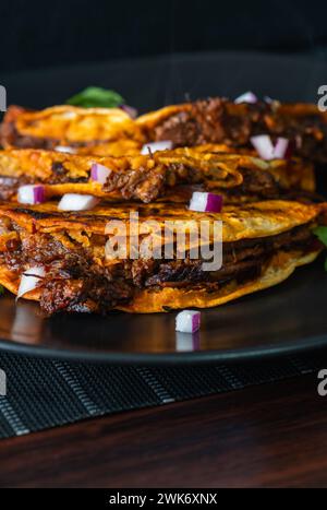 3 Beef Birria Tacos Stacked on Black Plate Stock Photo