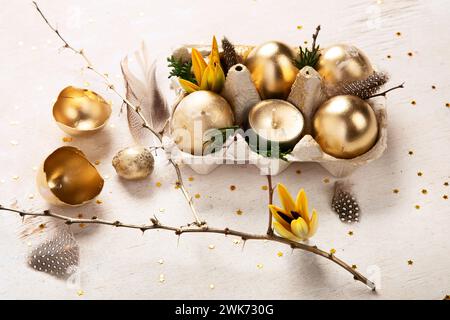 Stylish golden eggs easter concept. Easter gold eggs with flowers on light background. Happy easter card. Top view. Stock Photo