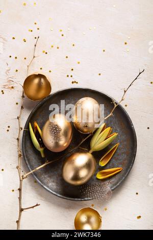 Stylish golden eggs easter concept. Easter gold eggs with flowers on light background. Happy easter card. Top view. Stock Photo