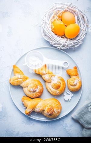Buns made from yeast dough in a shape of Easter bunny and colored eggs Stock Photo