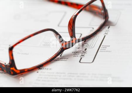 The glasses are lying on the open instructions for electronic equipment. Stock Photo