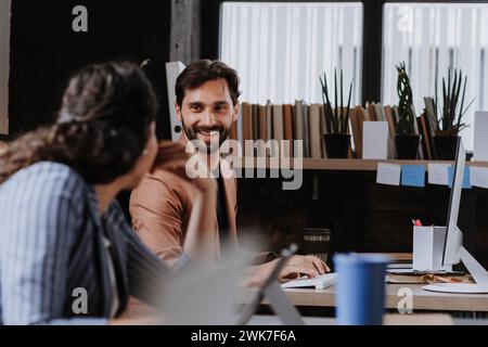 Two freelancers talking while working in shared work area. Concept of coworking, common workspaces for business, startups. Stock Photo