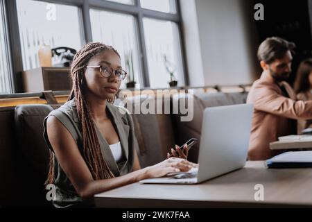 Beautiful businesswoman working on laptop in modern office. Group of freelancers working in shared work area. Concept of coworking, common workspaces Stock Photo