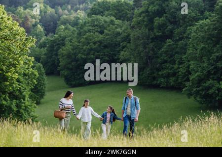 Family on interesting walk in forest, going through meadow. Successful mushroom, herbs medical plants or flowers picking, foraging. Concept of family Stock Photo