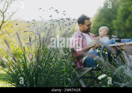 Low angle shot of man working outdoors in the garden, eating lunch, sandwich. Businessman working remotely from homeoffice, thinking about new Stock Photo