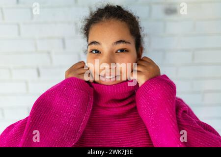 Portrait of beautiful curvy woman holding collar of pink turtleneck sweater, looking at camera. Stock Photo