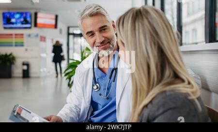 Pharmaceutical sales representative talking with doctor in modern clinic. Ambitious female medical rep presenting new medication. Female hospital dire Stock Photo