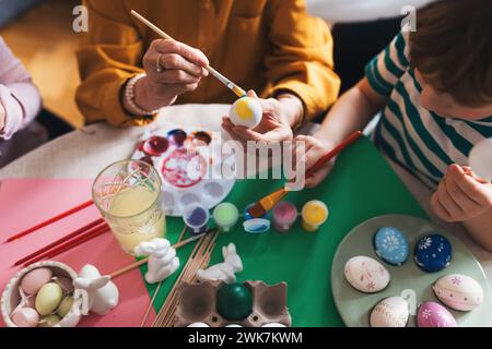 Close up of decorating easter eggs at home. Tradition of painting eggs with brush and easter egg dye. Stock Photo