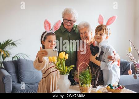 Grandparents taking selfie with grandchildren before traditional easter lunch. Recreating family traditions and customs. Happy easter. Stock Photo
