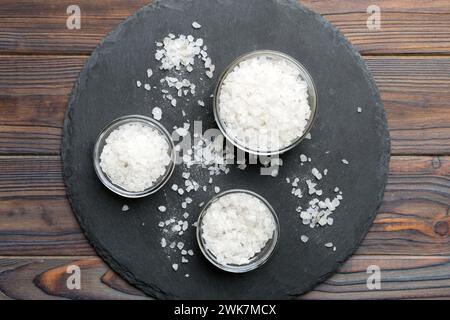 A wooden bowl of salt crystals on a wooden background. Salt in rustic bowls, top view with copy space. Stock Photo
