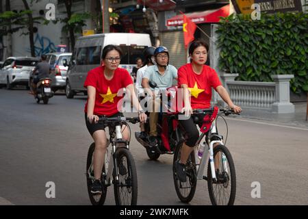 Women wearing National Day Vietnamese flag t-shirts riding bicyles around Hoan Kiem Lake in Hanoi, Vietnam Stock Photo