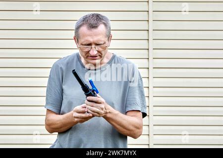 Middle aged man installs drinking water connection pipeline using valve fitting with compression connection. Stock Photo