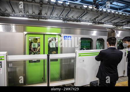 Crowded packed train Tokyo,Japan as male commuter waits for doors to open and door barrier to lift,Asia,2023 Stock Photo