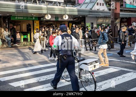 Tokyo male police officer pushing his bicycle across pelican crossing at Harajuku railway train station, Tokyo ward,Japan,Asia,2023 Stock Photo