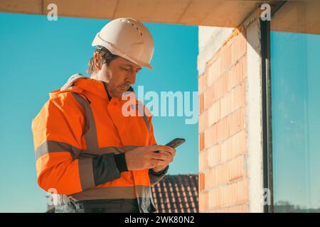 Construction engineer using mobile smart phone on site during inspection, selective focus Stock Photo