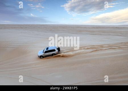 A Toyota Land Cruiser climbing up the desert mountain in Sealine Sand Dunes, Mesaieed, Qatar. Stock Photo