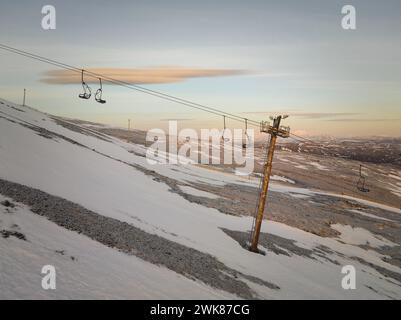 Cableway over hilly slope covered by snow on winter day Stock Photo