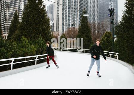 Teenage boy ice skate in downtown area in winter together Stock Photo