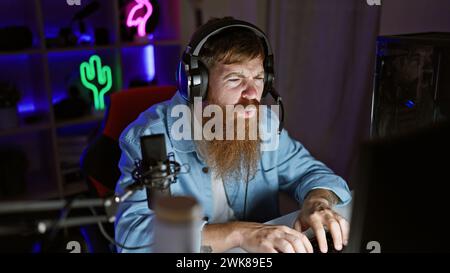 Handsome irish redhead streamer locked in serious game on his decked-out gaming rig, night streaming session from his decked-out gaming room Stock Photo