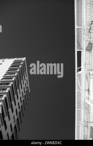 A low angle of two towering buildings in grayscale Stock Photo