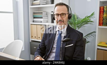 Middle age man with grey hair business worker wearing headset speaking at the office Stock Photo