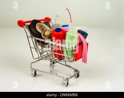 A shop cart with threads, sewing accessories and buttons. White background. Place for text or logo. Stock Photo