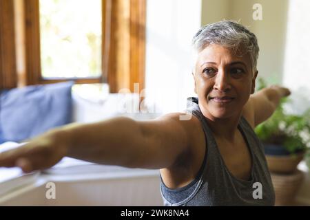 A mature biracial woman stretches during a home workout Stock Photo