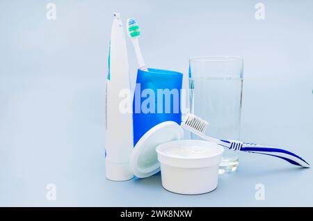 Bowl with tooth powder and brush, glass of water and toothpaste on a blue background Stock Photo