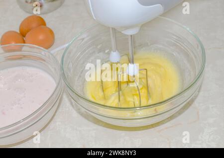 Egg yolks are whisked with sugar in the mixer bowl Stock Photo