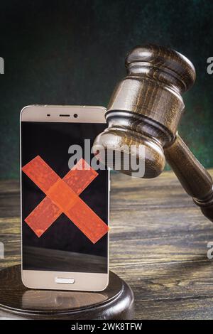 Judge gavel with a smartphone with a taped screen.Communications ban or trade restrictions on smartphone shipments concept Stock Photo
