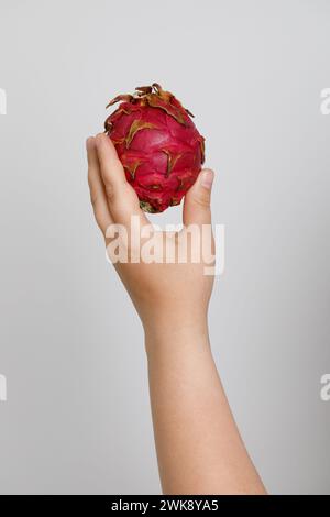 Fresh pitahaya in female hand on white background. Dragon fruit. Stock Photo