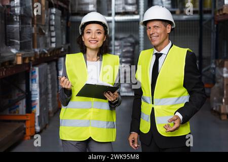 professional headshot, middle aged supervisor and female employee in hard hat with clipboard Stock Photo