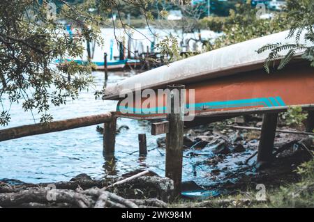 Boat turned down on the edge of a river on a cloudy day. Stock Photo