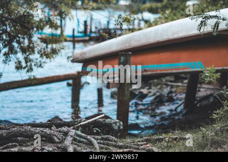 Boat turned down on the edge of a river on a cloudy day. Stock Photo